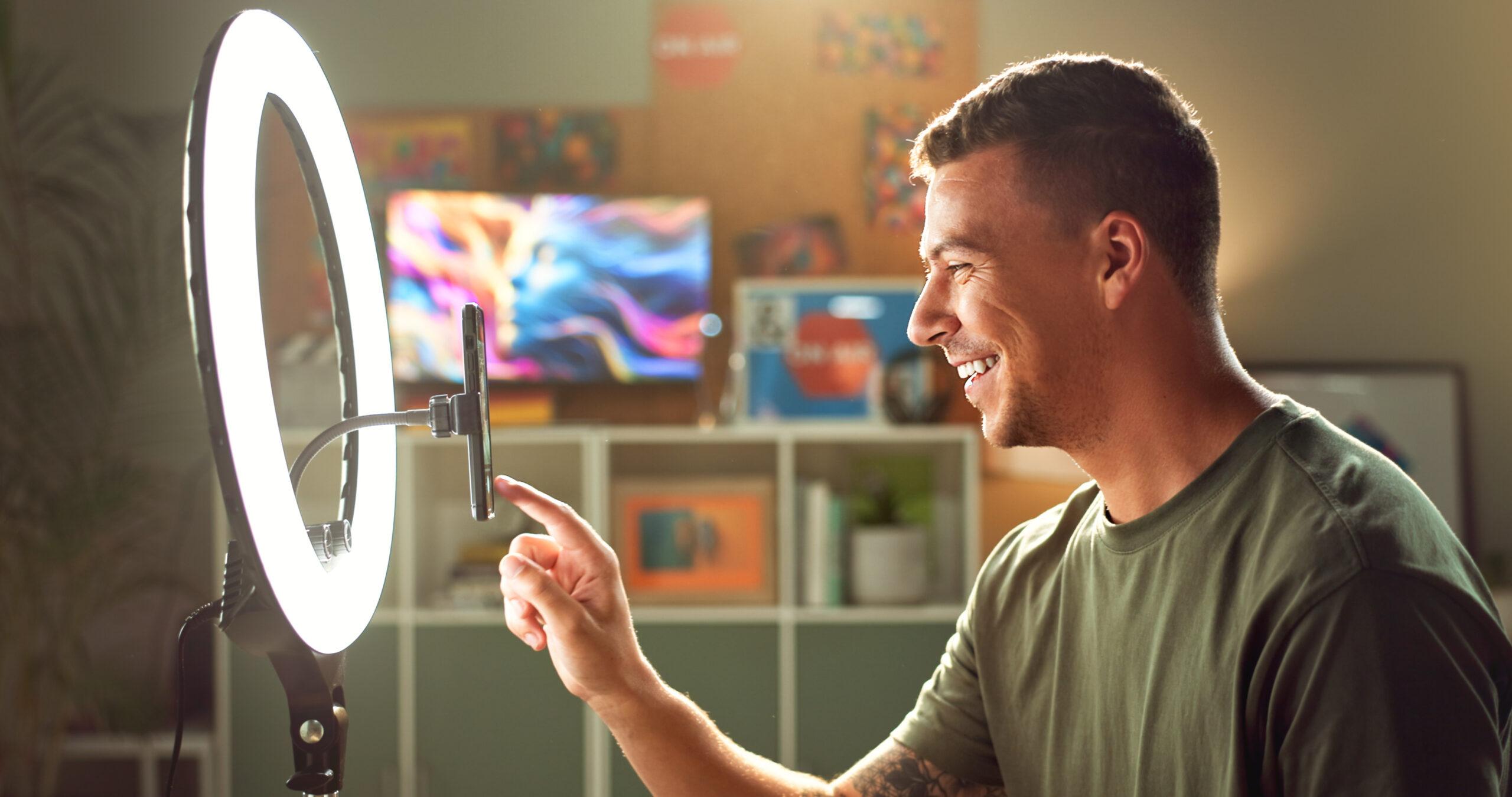 influencer-suena-la-luz-y-sonrie-en-el-telefono-para-la-interaccion-de-seguidores-de-transmision-y-la-creacion-de-contenido-hombre-jugador-y-movil-en-el-hogar-para-la-introduccion-de-compromiso-de-su